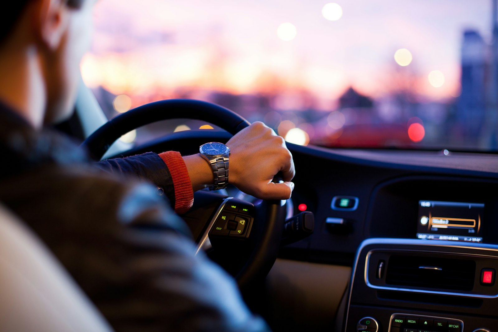 View across a clean car dashboard and steering wheel at dusk.