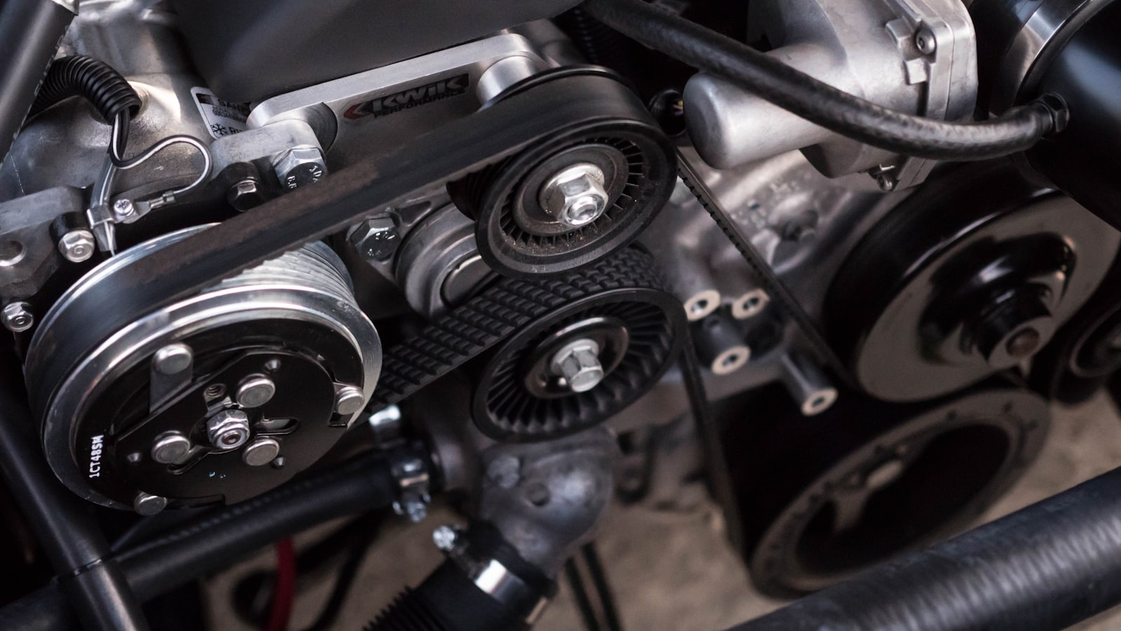 Close view of an engine's serpentine belt running over pulleys.